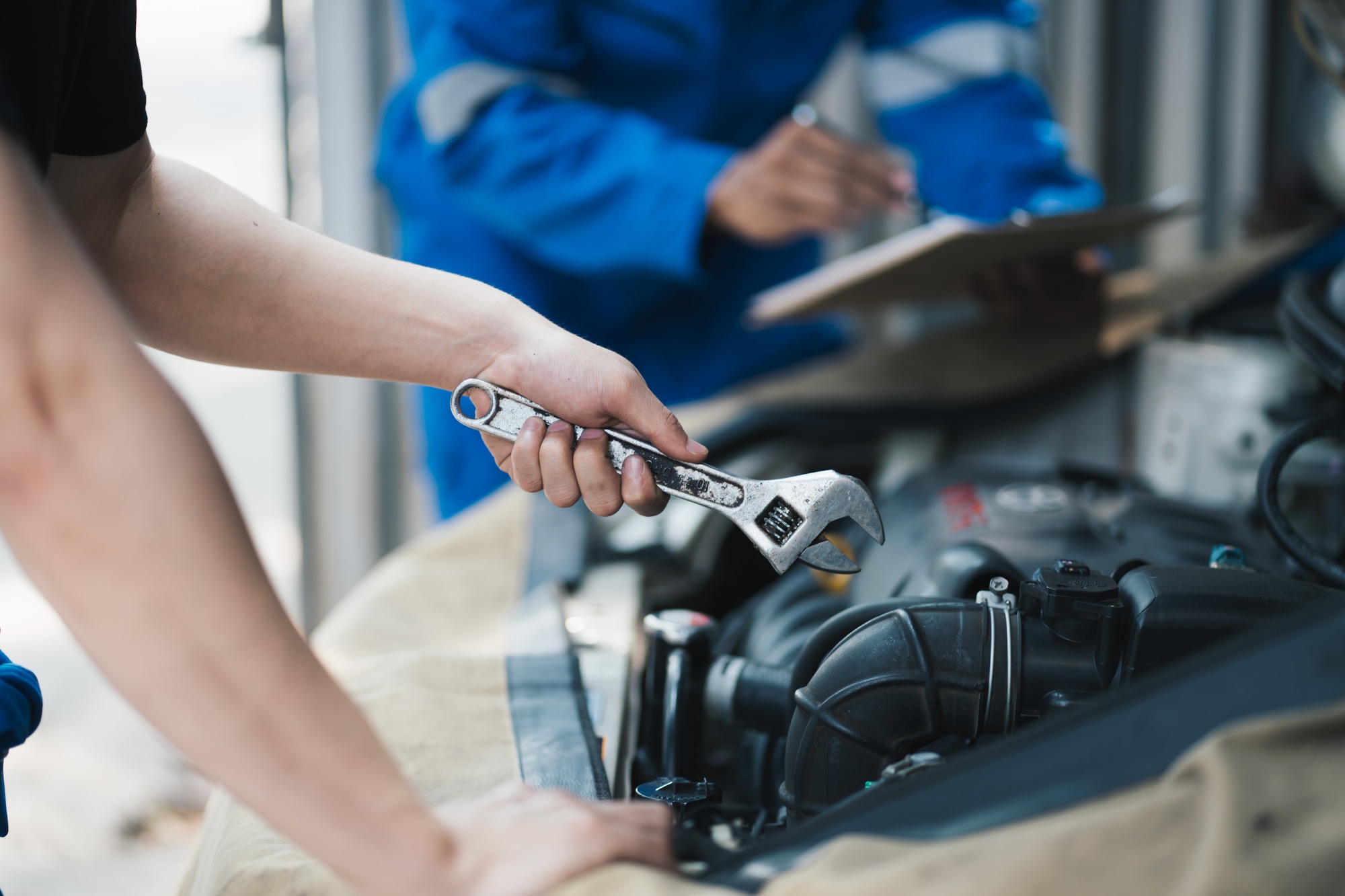 Auto mechanic or smith with wrench at car workshop